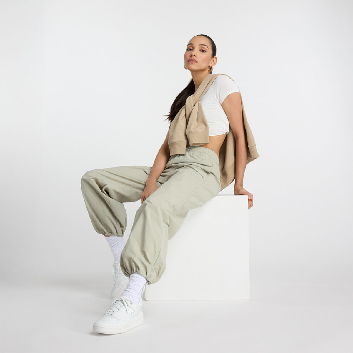 Young lady sitting on a white box with a jacket tied around her. 